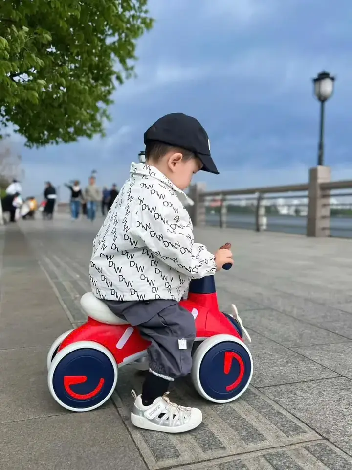 Bé sử dụng xe chòi chân màu đỏ ngoài trời