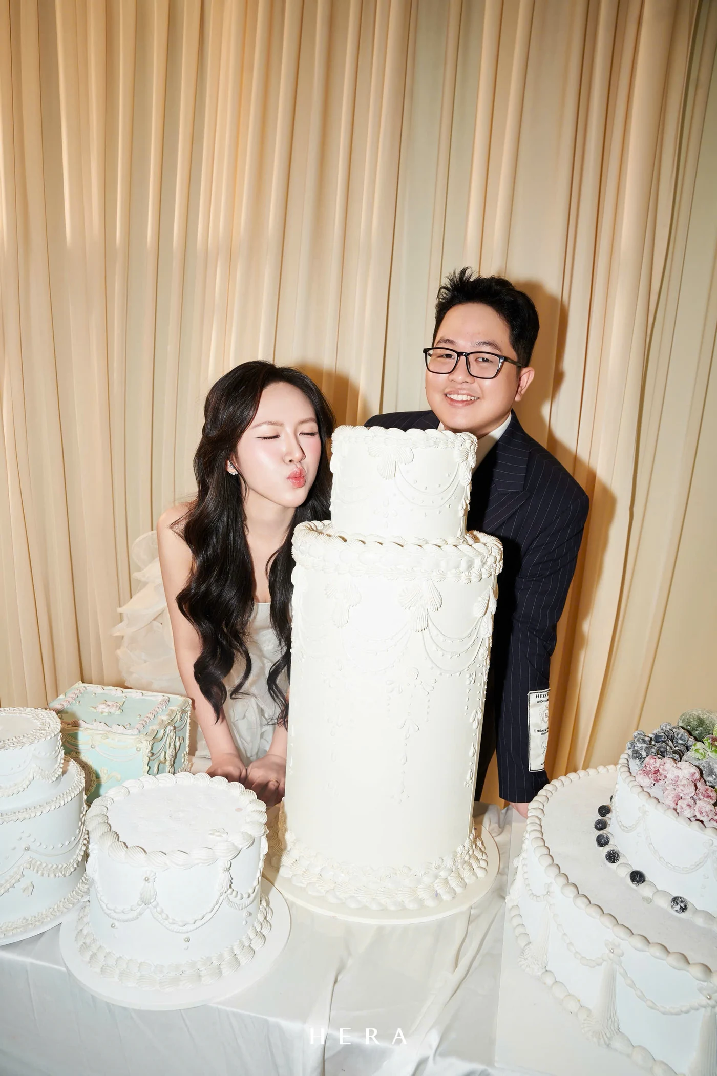 Tuấn Linh và Anh Thư bên những chiếc bánh cưới trắng trong căn phòng màu kem