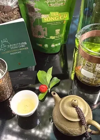 Chén trà, ấm đất và túi Trà Sông Cầu trên bàn kính