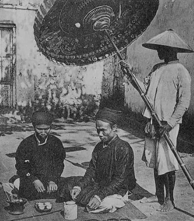 Ảnh tư liệu Miền Bắc 1884–1886: hai vị quan ngồi dùng trà, người hầu đứng che lọng