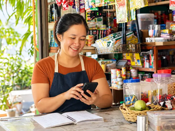 Chủ cửa hàng tạp hóa vui vẻ quản lý bán hàng trên điện thoại