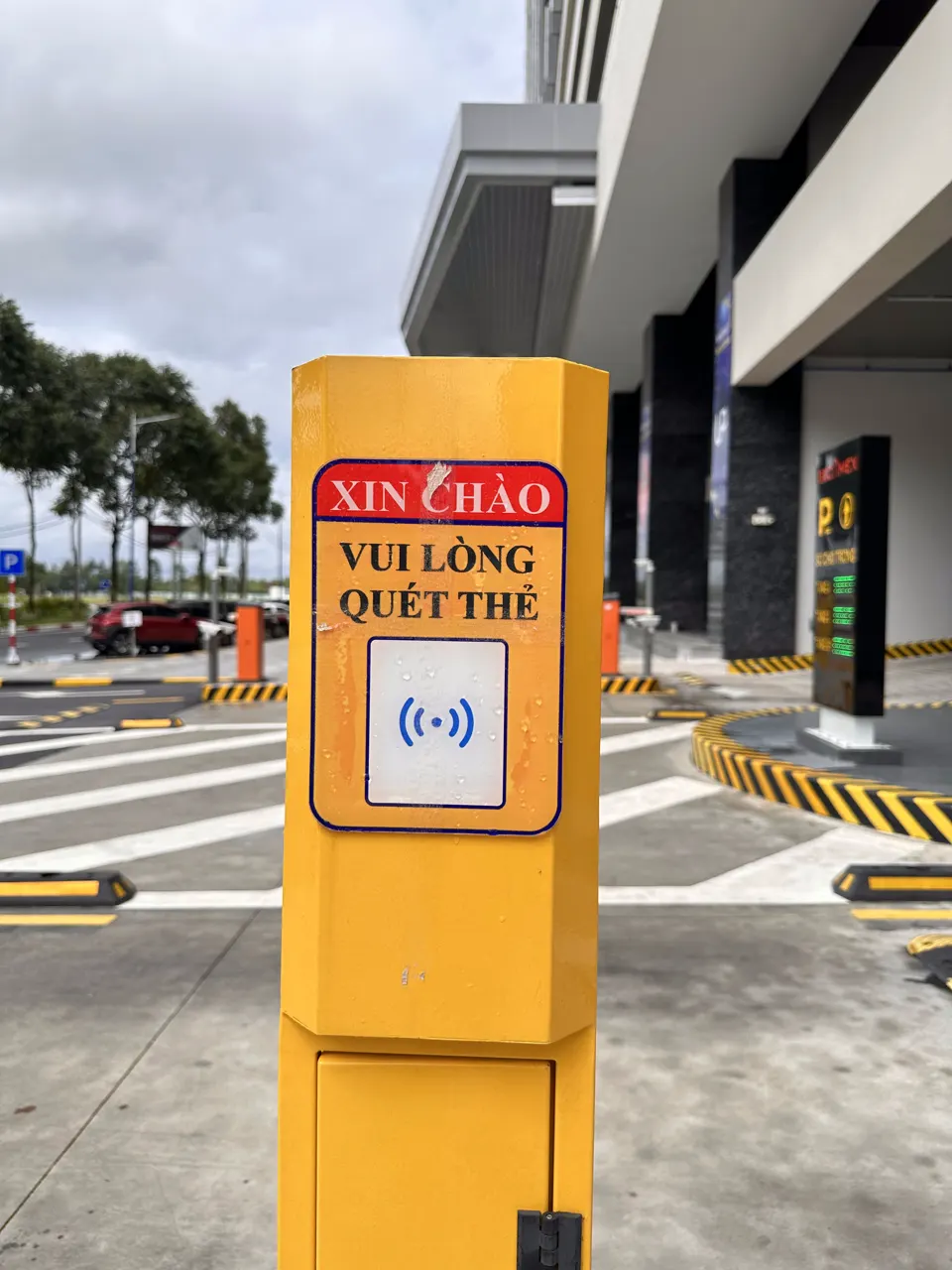 Trụ đầu đọc thẻ màu vàng ở cổng với dòng chữ Xin chào, vui lòng quẹt thẻ
