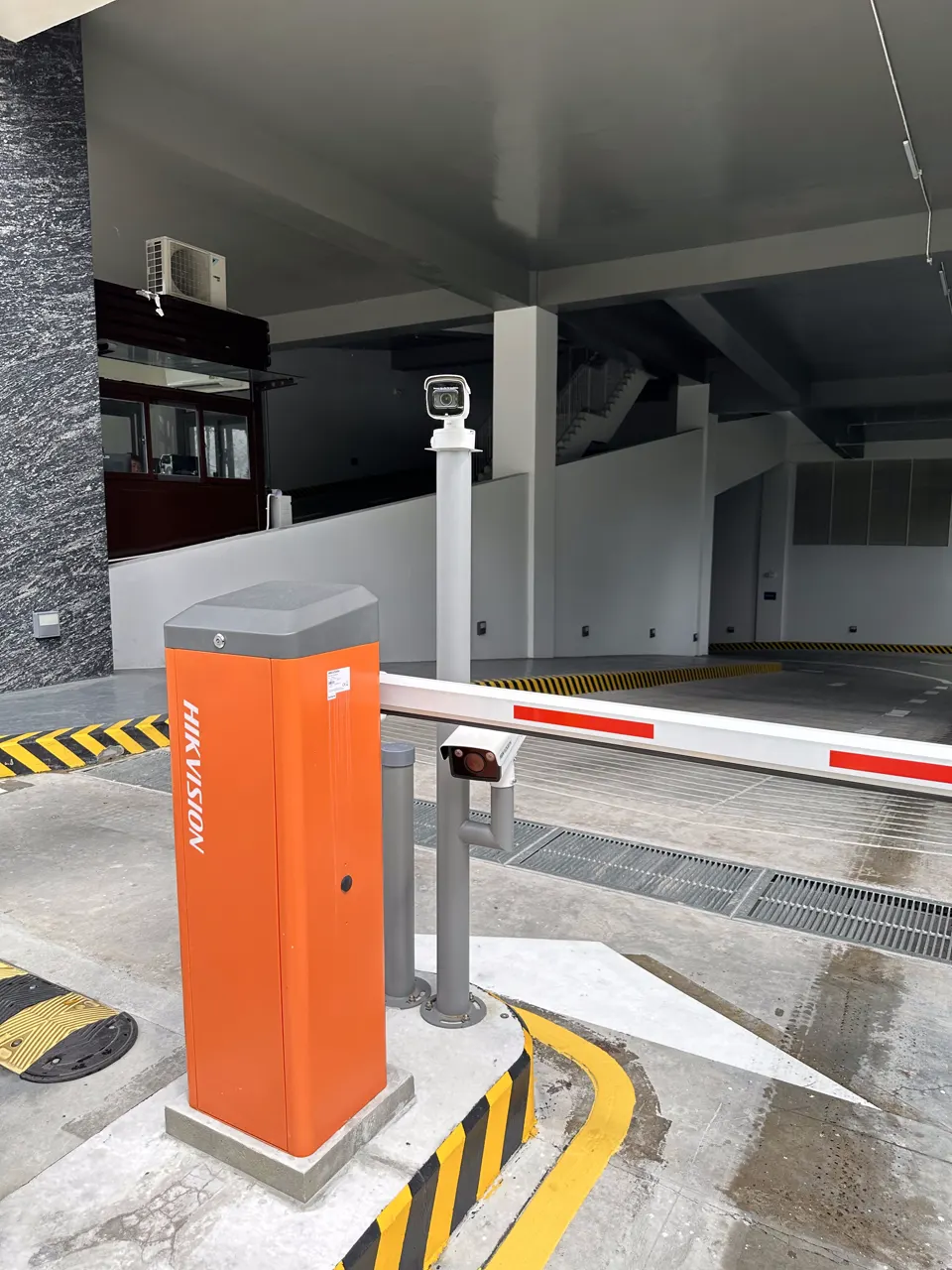Barrier tự động màu cam ở làn xe vào, phía sau là trụ camera