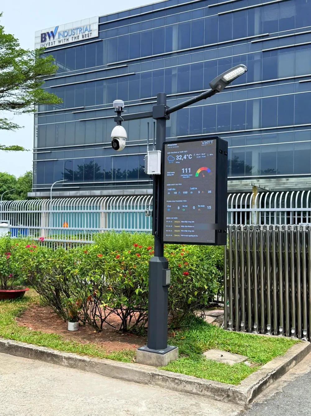 Trụ Smart Pole nhìn từ lối xe ra vào, phía sau là tòa nhà văn phòng kính