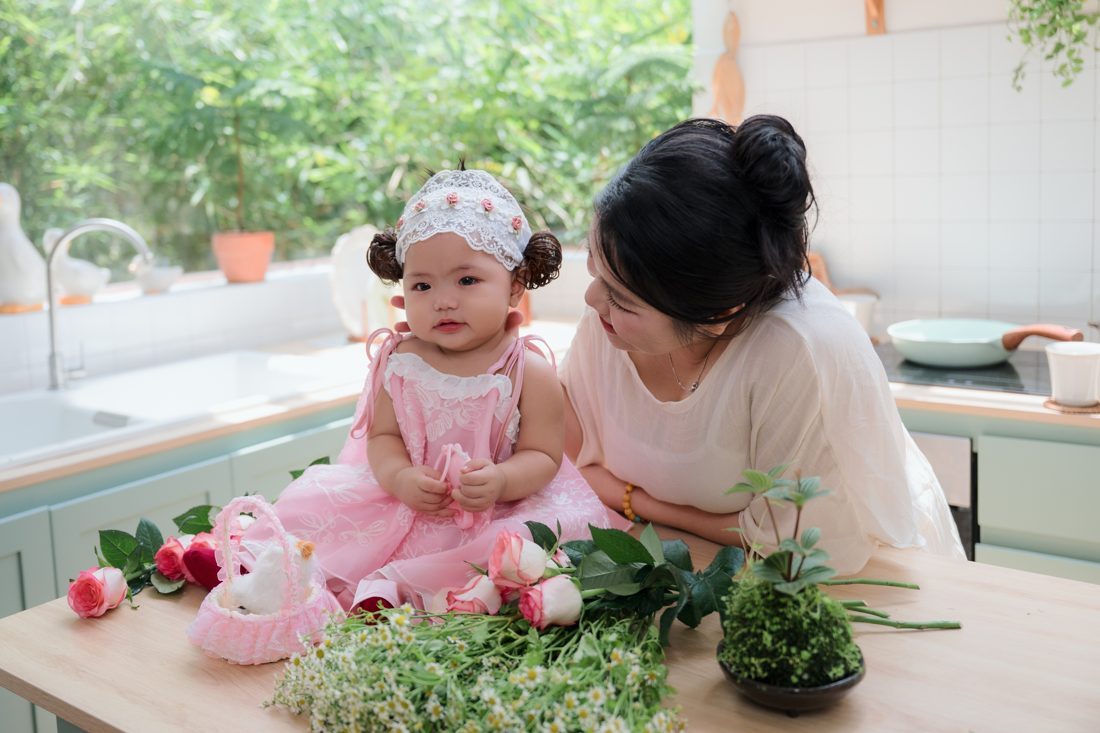 Chị Phan Huệ nghiêng đầu nhìn con gái đang ngồi trên bàn bếp