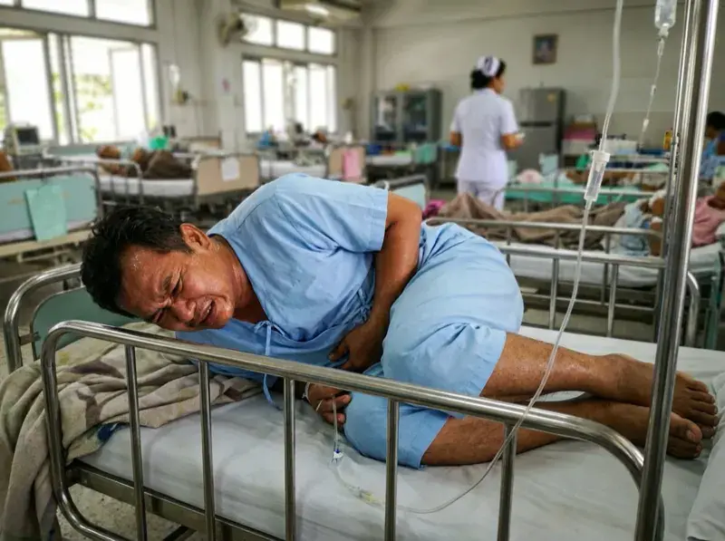 ผู้ชายนอนกุมท้องด้วยความเจ็บปวดในโรงพยาบาล