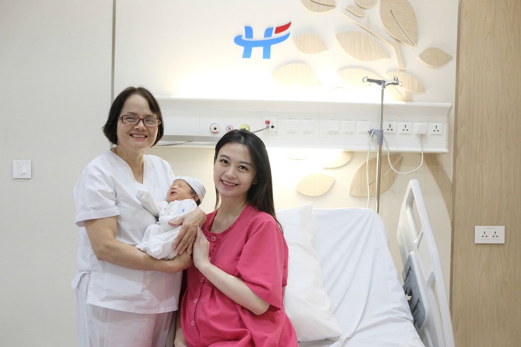 Mẹ bế con cùng bác sĩ tại phòng hậu sản